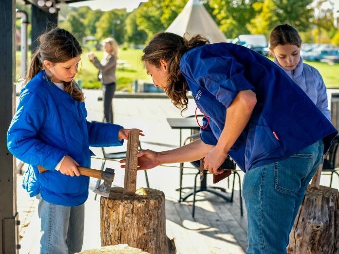 Underviser og elev arbejder med økse på træ til snelle