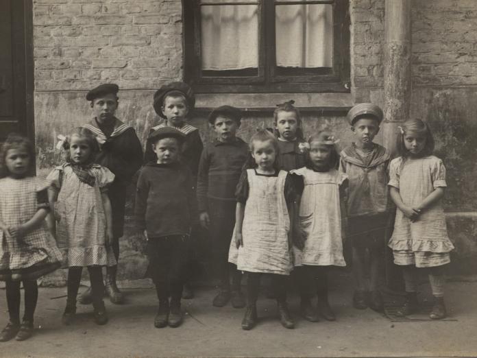 Sort hvidt foto af børn opstillet i baggård, omkring 1900. 