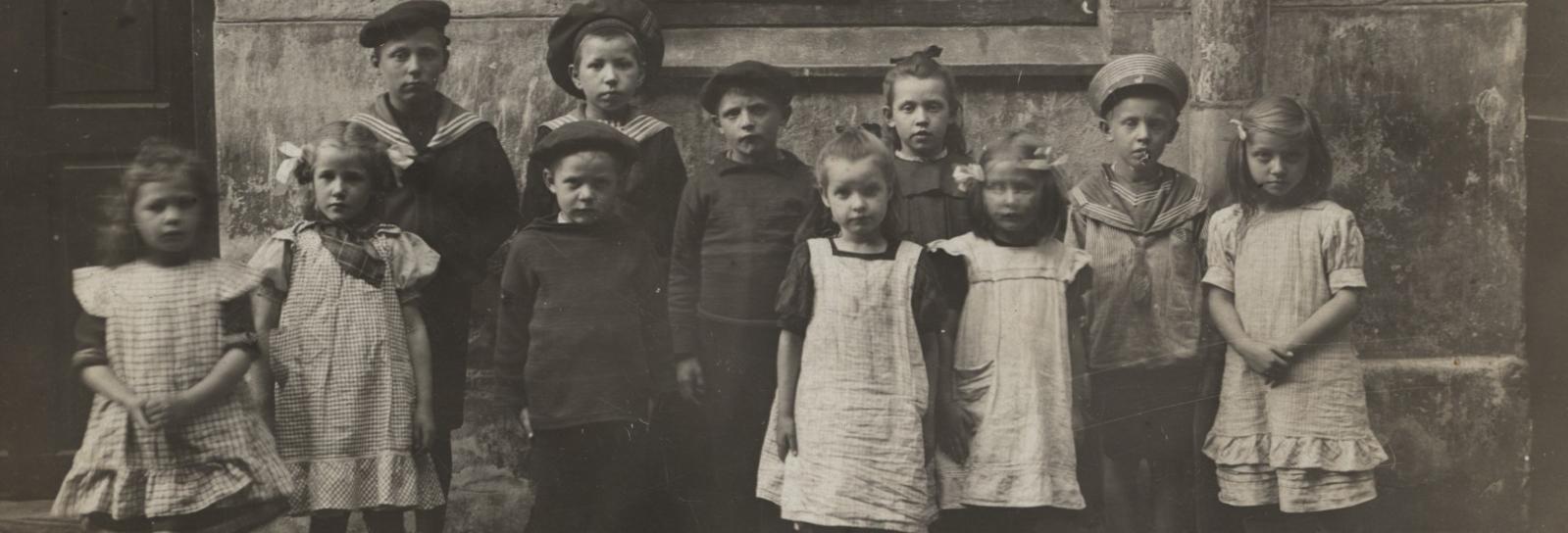 Sort hvidt foto af børn opstillet i baggård, omkring 1900. 