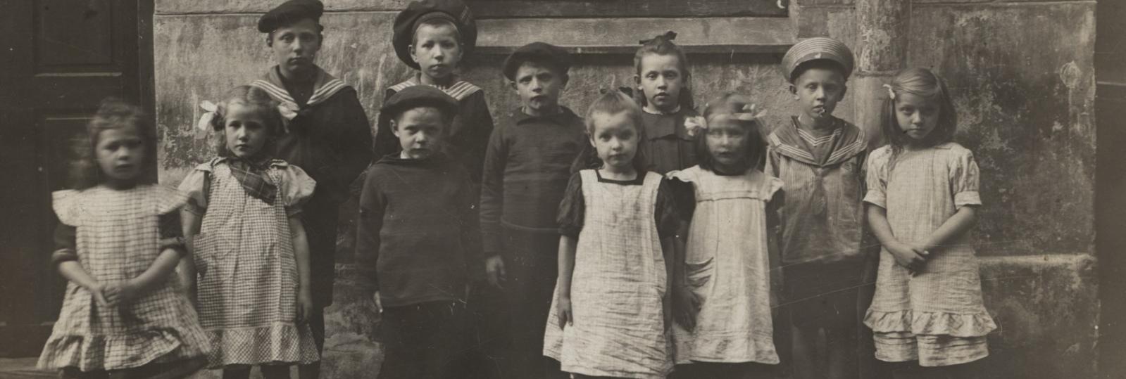 Sort hvidt foto af børn opstillet i baggård, omkring 1900. 