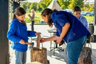 Underviser og elev arbejder med økse på træ til snelle