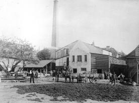 Fabrik. Skorsten. Hestevogne og arbejdsmænd.