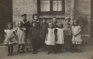 Sort hvidt foto af børn opstillet i baggård, omkring 1900. 